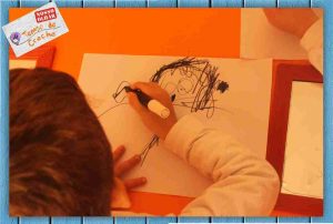 Arthur desenhando seu autoretrato após ajuda da Clara